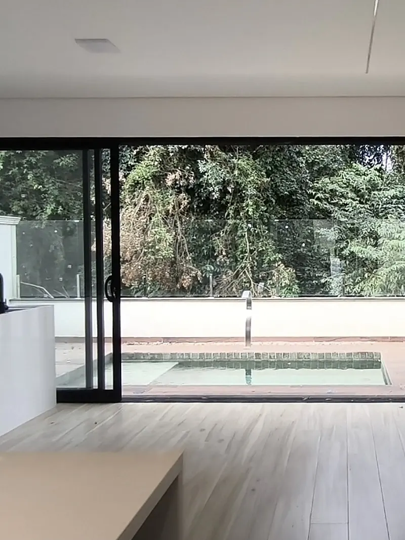 Sala com porta de vidro de ponta a ponta abrindo para a piscina